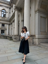 a lady wears a white jacquard knit top and a black mini skirt